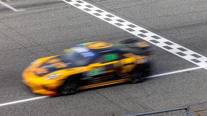 Fototapeta premium Motion blur, Race car racing on speed track, race car on road crossing start and finish line, Target business achieve and victory concept.
