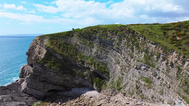 Ascending aerial shot of cliff with rock layers to reveal Jurassic coastline of Dorset near Lulworth Cove