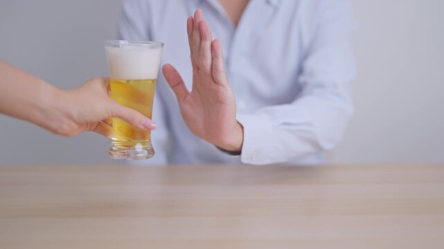 man making stop hand gesture to refuse a glass of Beer, Healthy man say no to alcohol drink, stop alcoholism and addiction concept. Responsible man reject a drink before driving and quit booze