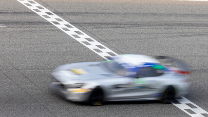 Fototapeta premium Motion blur, Race car racing on speed track, race car on road crossing start and finish line, Target business achieve and victory concept.