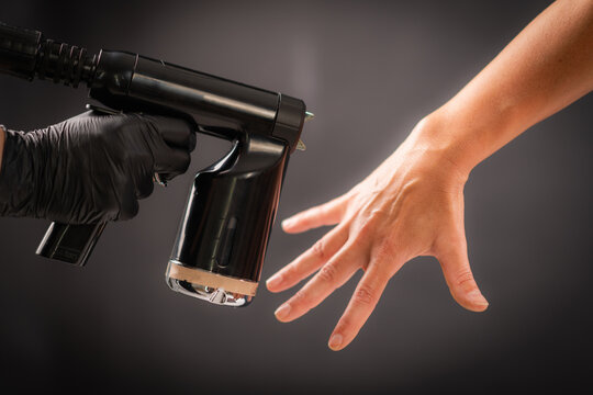 Spraying tanning solution across the hand using a handheld device. Even distribution ensures consistent pigmentation and balanced cosmetic appearance.