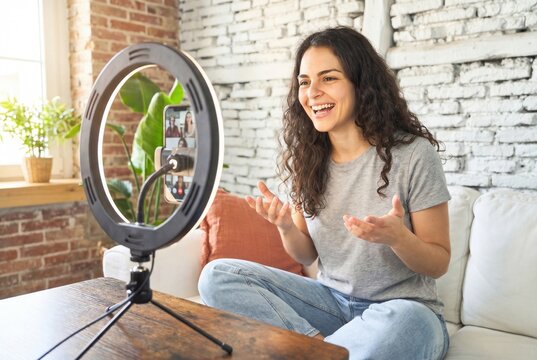 Young woman talking to camera, streaming video content from home