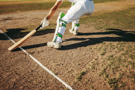 A cricket player keeping the bat behind the crease during a game on a sunny day
