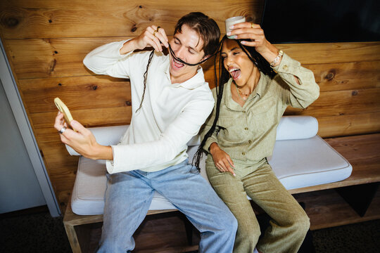 Two friends laughing while taking a selfie at home having fun