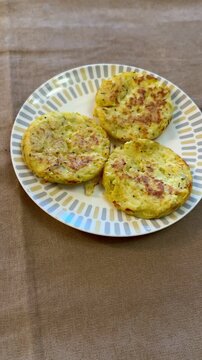 Three potato pancakes on plate, crispy golden draniki seasoned with pepper and herb flakes, served on patterned ceramic plate.