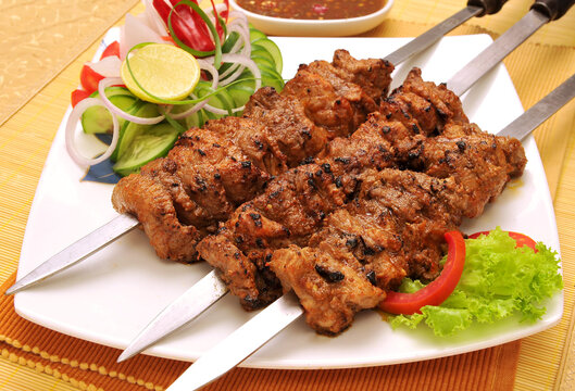 Spicy Grilled Beef Bihari boti BBQ with fresh salad on a white plate