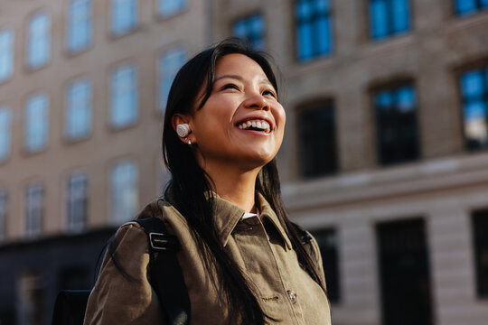 Smiling woman enjoying a city walk with earbuds