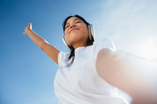 Young woman listening to music, feeling freedom and joy