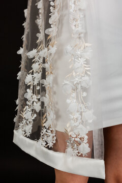 Bottom edge detail of a bridal tulle cape with white 3D flower decorations.