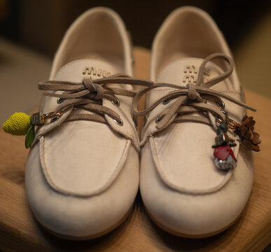 Beige leather boat shoes in a moccasin style, with leather laces and a Miu Miu logo on the tongue featuring removable charms.Milan - Italy,15 April 2026
