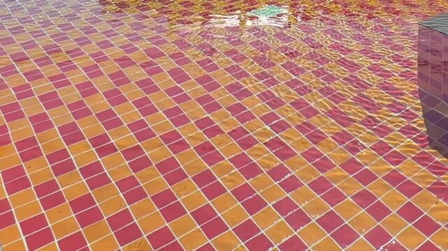 Video of swimming pool with red and yellow checkered tile pattern visible under clear water surface