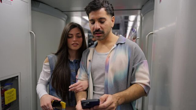 Young couple using a smartphone on a subway train
