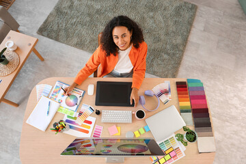 Naklejka premium Female African-American interior designer working with color palettes at table in office, top view