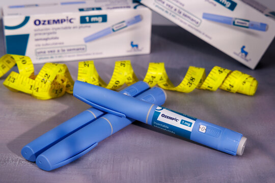 Blue Ozempic medication pens and yellow tape measure on a cement background for representing subcutaneous injection for obesity control. In Barcelona - Spain; March 22, 2026.