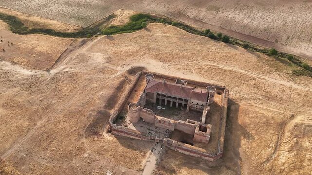 Aerial drone orbit around abandoned castle in dry countryside landscape
