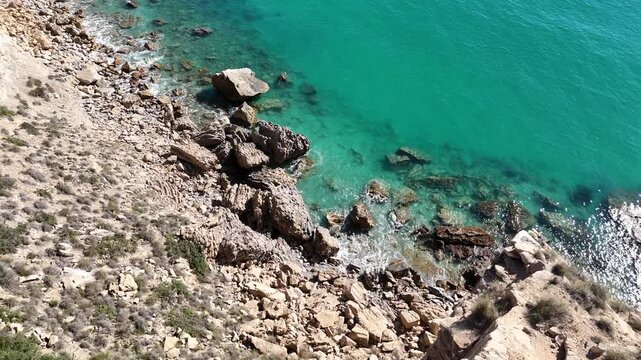 Top down drone shot pulling back over Mediterranean coast with waves breaking
