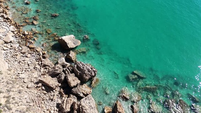Top down drone shot flying forward over Mediterranean coast with breaking waves
