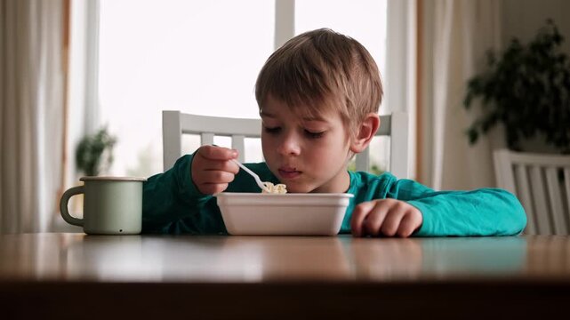 6 years old boy eats instant noodle from box. Child is eating Asian ramen. Lunch time. A good appetite. Tasty children food. Close-up portrait. Carbs dinner. Fast food. Kid eating by himself with fork
