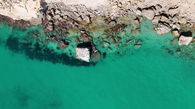 Top down drone shot flying toward open Mediterranean sea over breaking waves