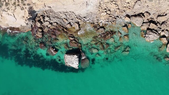 Descending top down drone shot over Mediterranean waves toward open sea