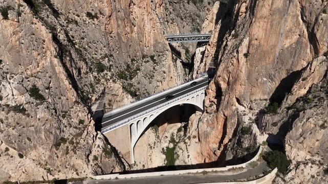 Descending static drone shot over Mascarat Canyon with bridges and road traffic