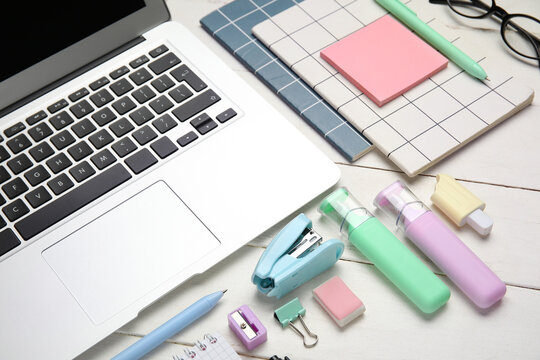 Composition with modern laptop and school supplies on white wooden background, closeup