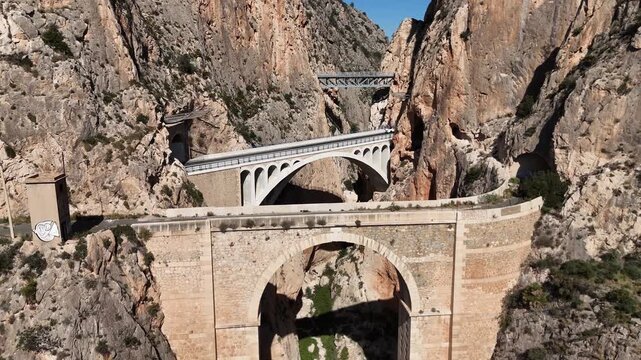Drone pulling back revealing Mascarat Canyon with three bridges and road traffic
