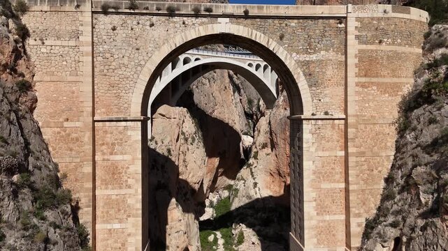 Ascending drone shot revealing Mascarat Canyon with three bridges and road traffic