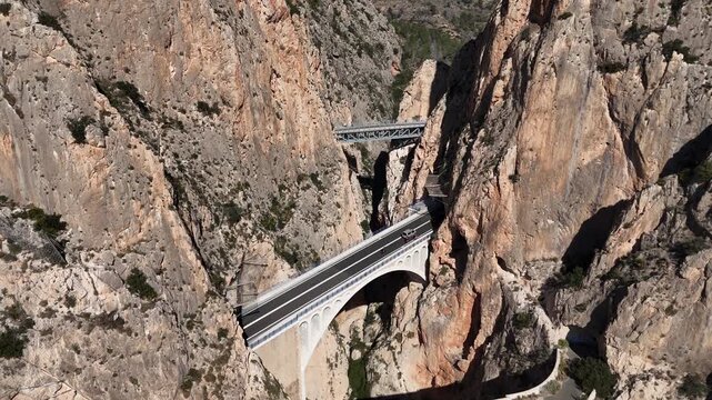 Forward ascending drone shot revealing Mascarat Canyon bridges and road traffic