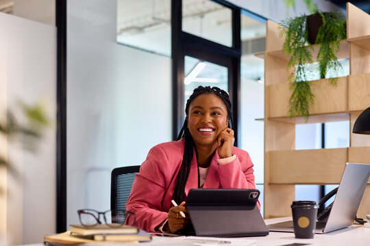 Smiling businesswoman looking up while thinking at office