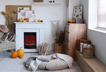 Obraz premium Interior of stylish living room with fireplace, armchair and pumpkins. Autumn concept