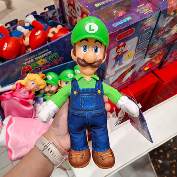 Person holding Luigi action figure from Super Mario Bros movie collection in a retail toy store display background on April 14, 2026 in Bangkok, Thailand