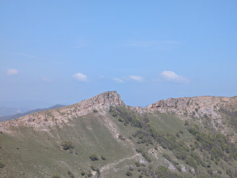 Paesaggio montano con montagne ondulate, vegetazione sparsa e cielo limpido, una scena naturale ampia e luminosa ideale per contenuti dedicati a natura, viaggio e outdoor