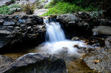 Fototapeta premium Beautiful small waterfall hidden in the forest during the summer in Chiang Mai, northern Thailand.