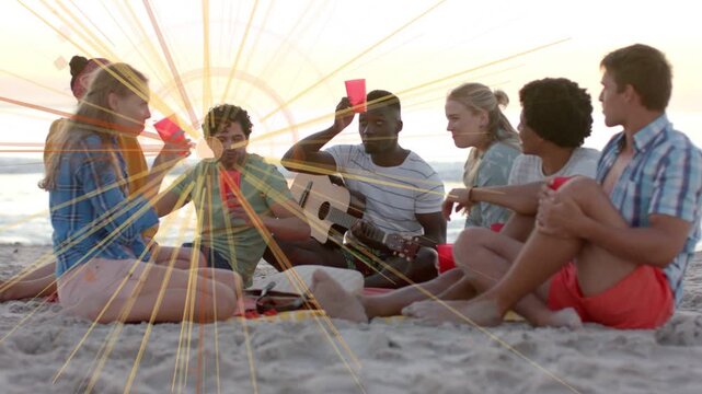 7 friends sitting on beach one raising red cups starting toast guitarist playing flare pulsing ads