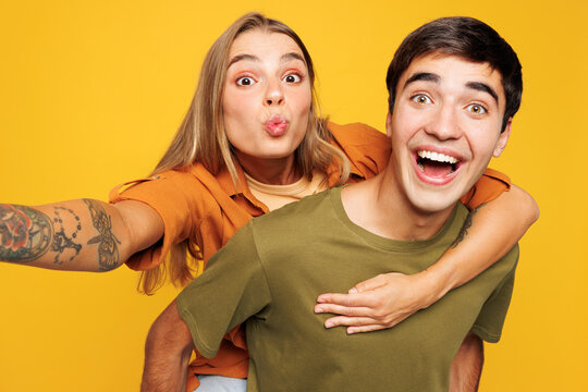 Close up young couple two friends family man woman wear casual clothes looking camera doing selfie shot pov on mobile cell phone together isolated on pastel plain light yellow color background studio.