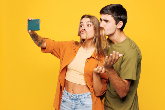 Young couple two friends family man woman wear casual clothes do selfie shot on mobile cell phone post photo on social network together isolated on pastel plain light yellow color background studio