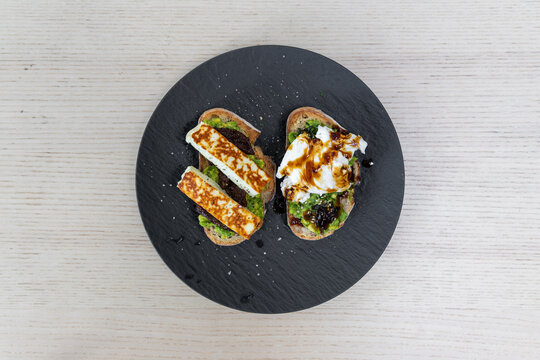 A plate of avocado toast with haloumi and poached egg.
