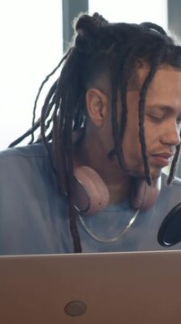 Creator sitting desk hearing laptop ping, turning toward mic, leaning, adjusting recording levels