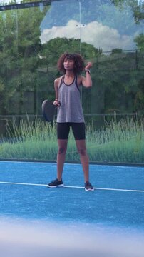 Vertical video: Reacting on cue, woman in tank and shorts warming up with paddle on blue court