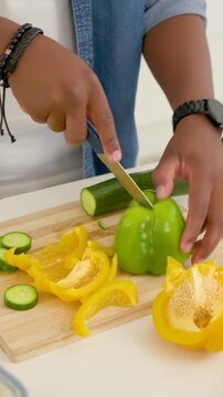 Vertical video: Placing green pepper, home cook slicing it on board in kitchen for prep in denim