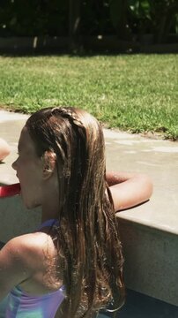 Vertical video: Girl leaning pool edge accepting watermelon from left, biting for summer food snack