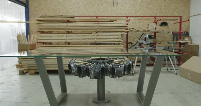 Modern glass top table with a radial engine base standing in a woodworking workshop