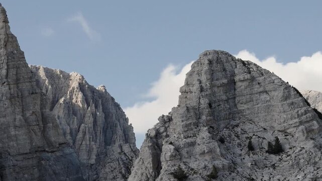 Aerial view of majestic, rugged mountains with sharp, jagged peaks contrasting against the soft blue sky and scattered white clouds, Teth, Shkoder County, Albania.