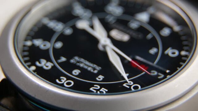 Macro close up of an automatic mechanical field watch with moving arms
