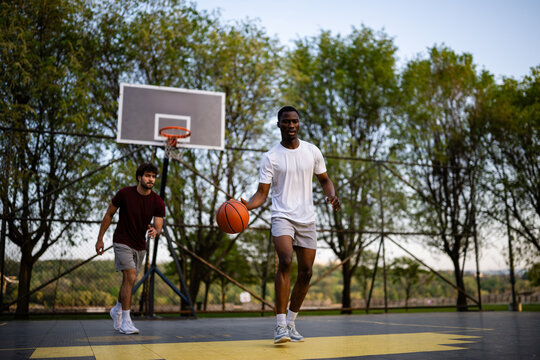 Young men playing basketball on outdoor court