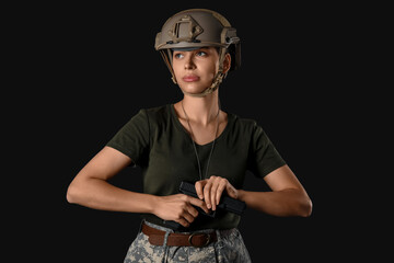 Obraz premium Confident young female soldier with handgun on black background