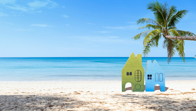 Miniature wooden house model on tropical beach, summer outdoor day light, property and real estate business