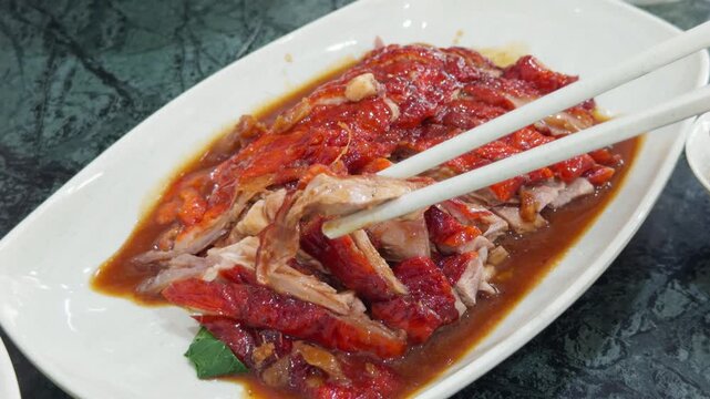 Chopsticks Picking Roast Duck with Red Sauce Close Up - Thai Chinese Crispy Roasted Duck Poured Sauce Dish