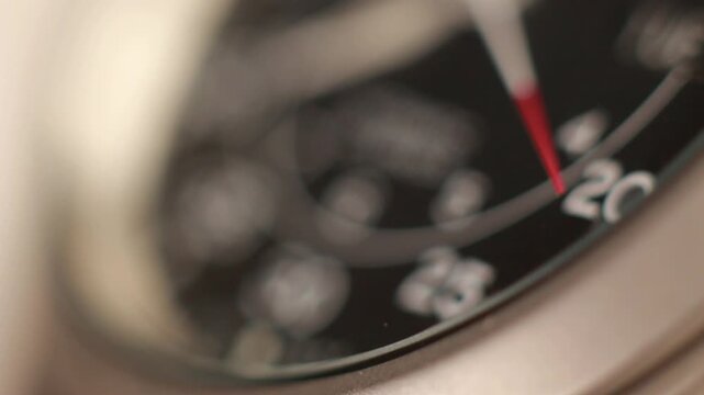 Macro close up of an automatic mechanical field watch with moving arms

